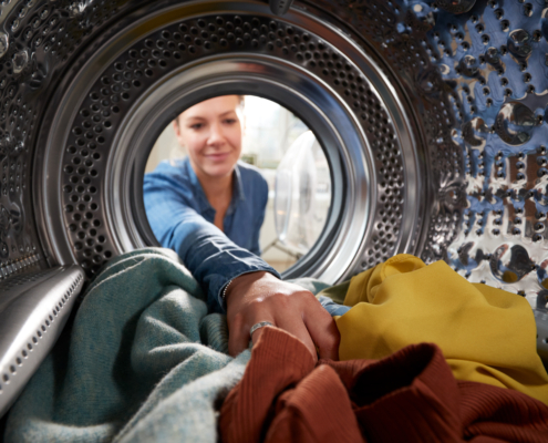 View Looking Out From Inside Dryer Machine As Young Woman Does Laundry
